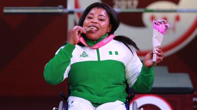 a female powerlifter bites her gold medal on the podium