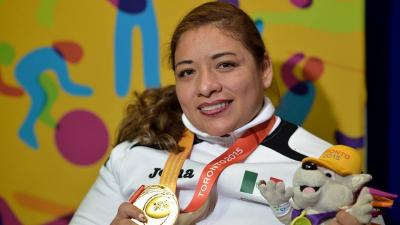 female powerlifter Amalia Perez holds up a gold medal and a toy mascot