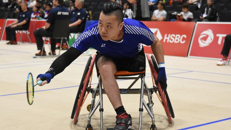 Hong Kong badminton player in wheelchair leans over to return a shot