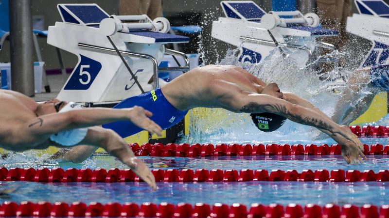 a male Para swimmer jumps backwards into the water