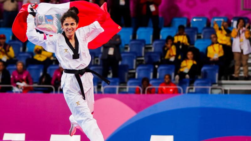 a female Para taekwondo athlete carrying the Peru flag