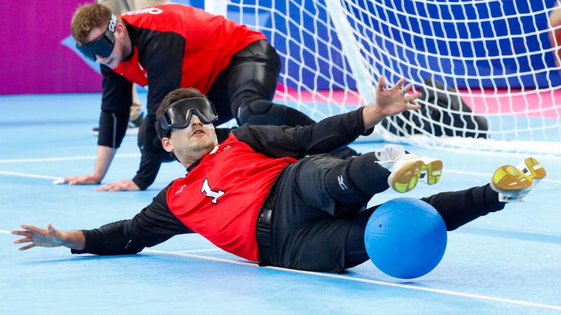 a male goalball player saves a shot with his legs