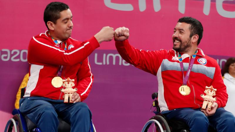 two male wheelchair table tennis players bump fists