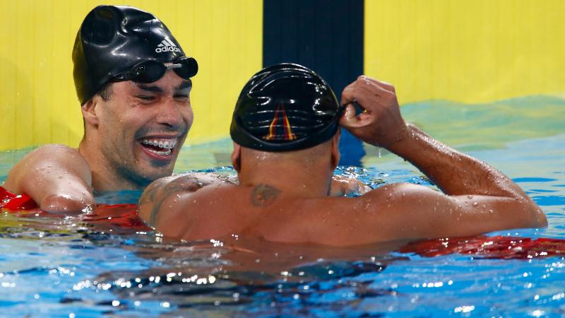 two male Para swimmers laughing in the water