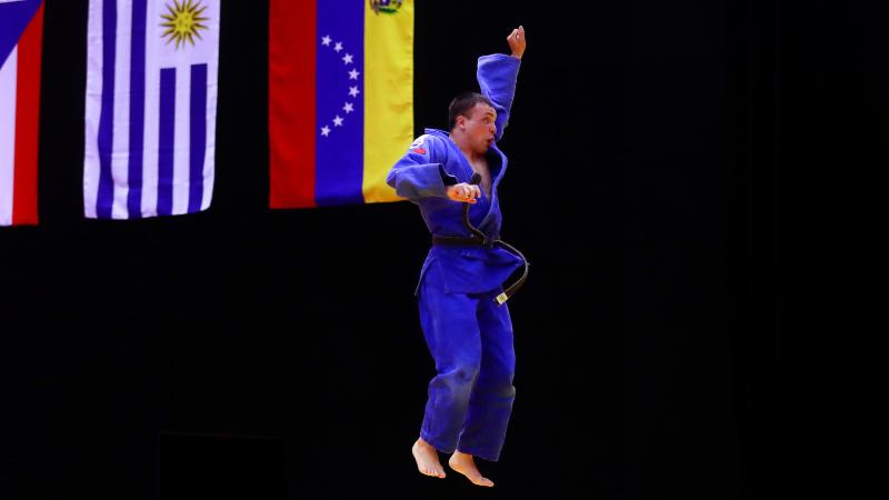 a male judoka jumps in the air in celebration
