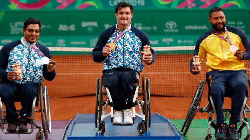 three male wheelchair tennis players on the podium with their medals