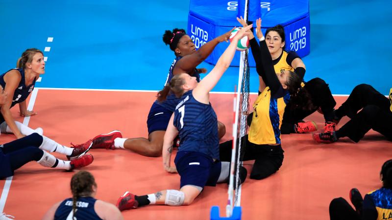 female sitting volleyball players contesting the ball over the net