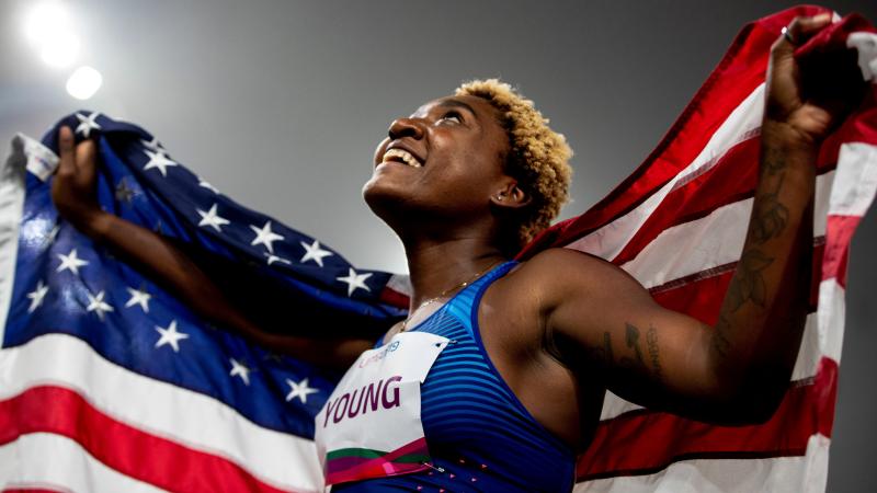 a female Para athlete holds up the United States flag
