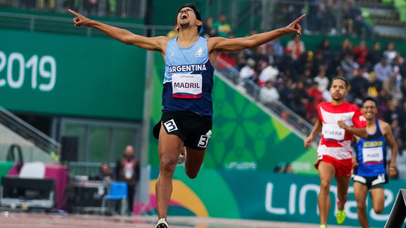 a male Para athlete celebrates with his arms wide