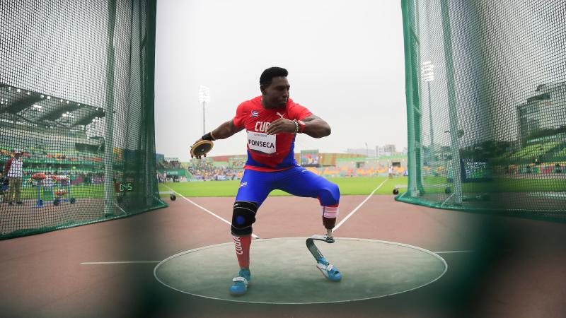 a male Para athlete with a prosthetic leg prepares to throw a discus