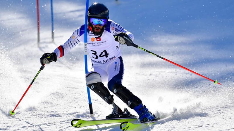 a male Para alpine skier on a prosthetic leg goes through a gate