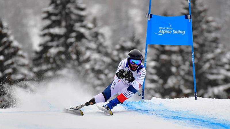 a male Para alpine skier with a prosthetic skiing round a gate