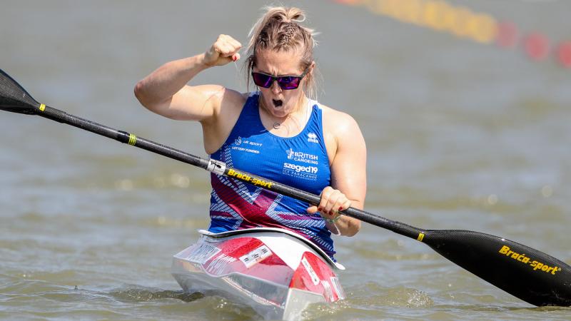 Woman in kayak clutches fist in celebration