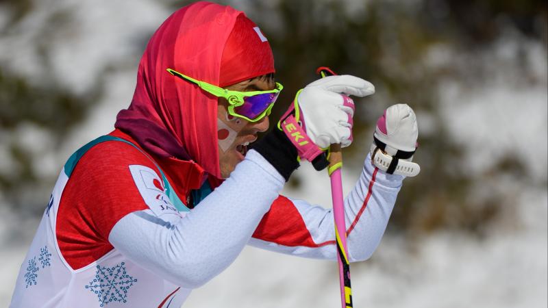 a male Para Nordic skier with one hand pushes through the snow
