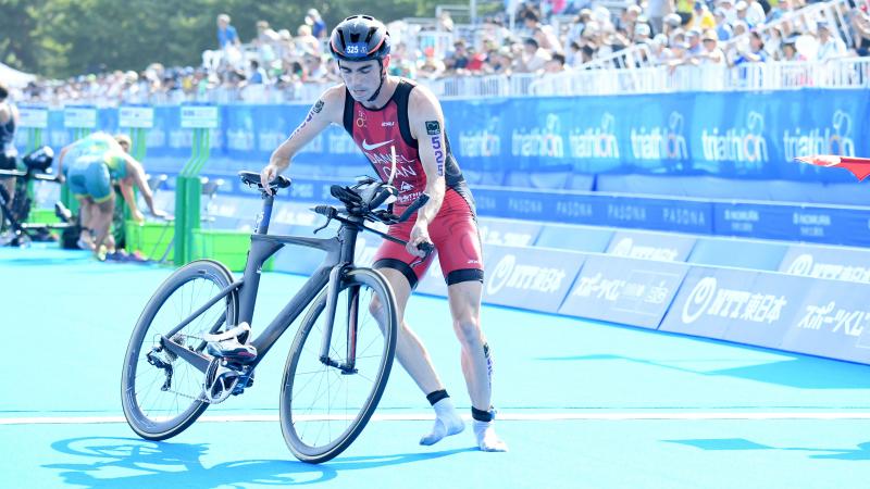 a male Para triathlete turns to get onto his bike