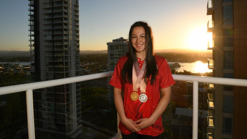 a female Para swimmer standing on a balcony with two medals around her neck