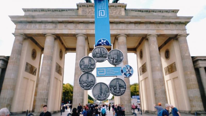 A marathon medal being shown in front of the Brandenburg Gate in Berlin
