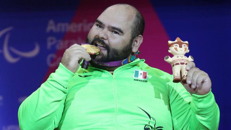 a male powerlifter bites his gold medal
