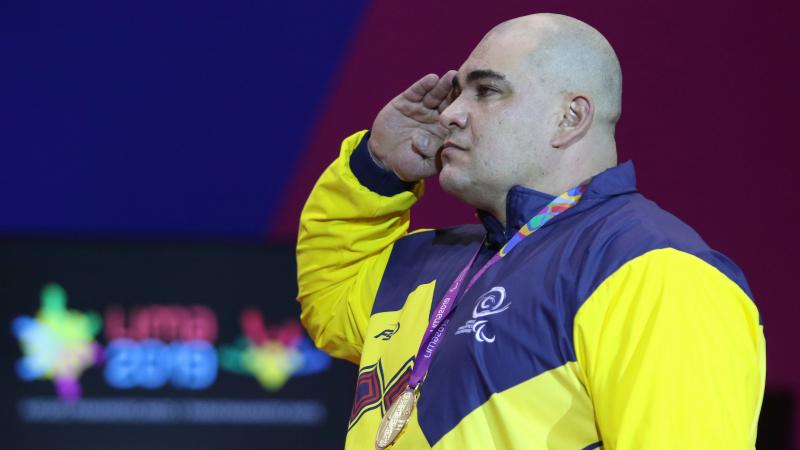 a male powerlifter salutes on the podium