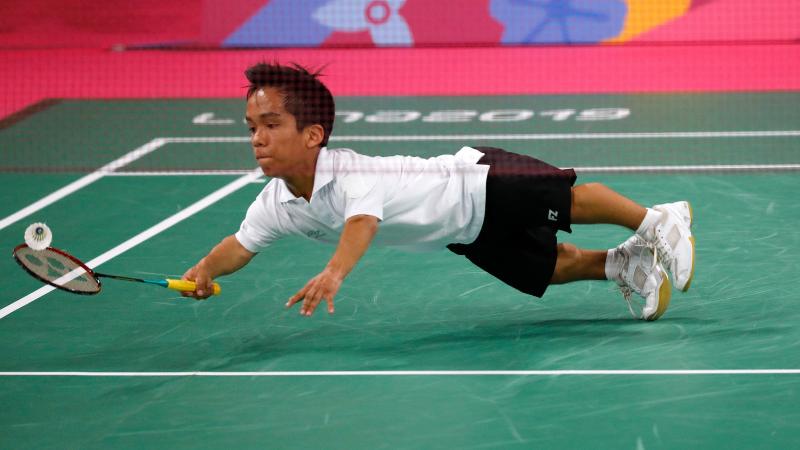 a male Para badminton player dives to hit a shot