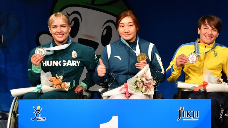 Four female wheelchair fencers holding up their medals