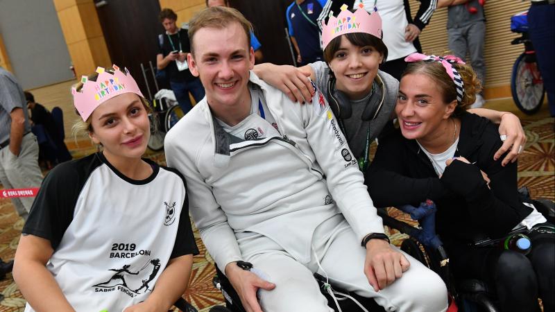 Male wheelchair fencer surrounded by friends for birthday