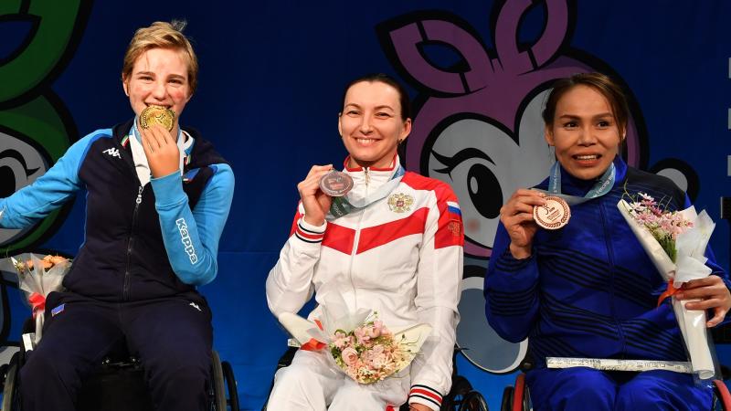 Four women pose on the podium holding their medals