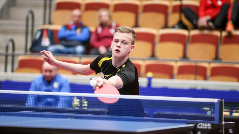 Teenage male table tennis player returns ball