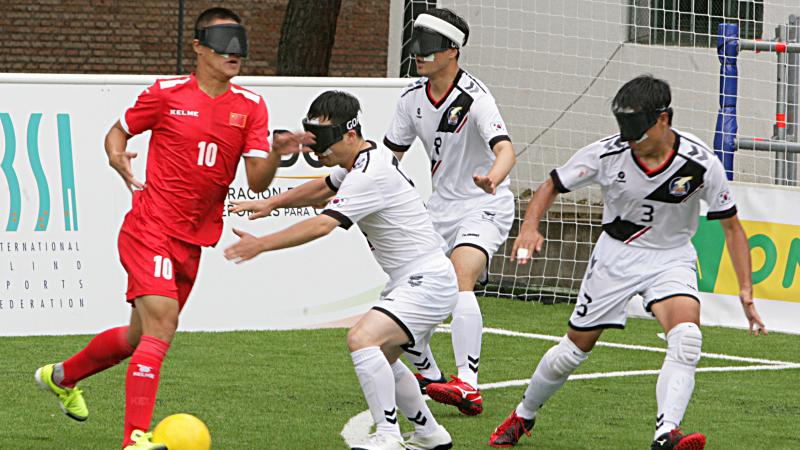 blind football player taking the ball while defenders try to intercept him