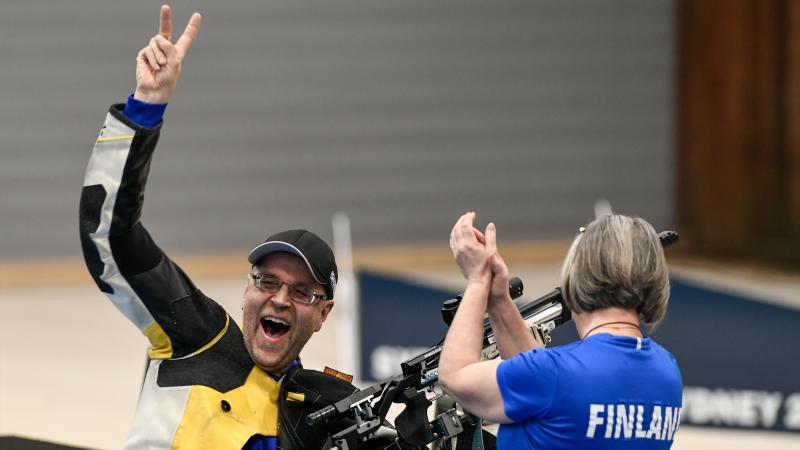 A male shooter celebrating together with a woman with a shirt written Finland
