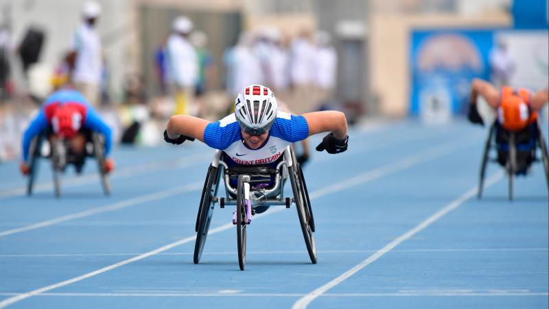 A female wheelchair racer crossing the line ahead of two other competitors