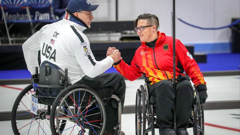 Two wheelchair curlers shake hands