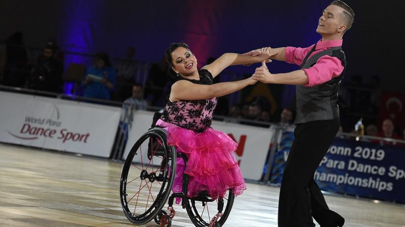 Female dancer in wheelchair and standing male partner dance to quickstep