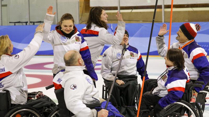 Group of Czech Republic wheelchair curlers high five each other
