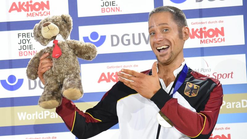 German dancer in wheelchair smiles with teddy bear prize
