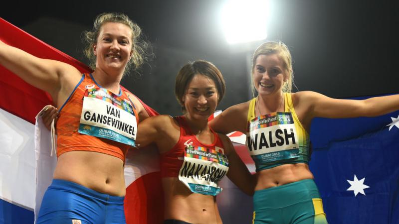 Three female longer jumpers pose for a photo with their respective flags