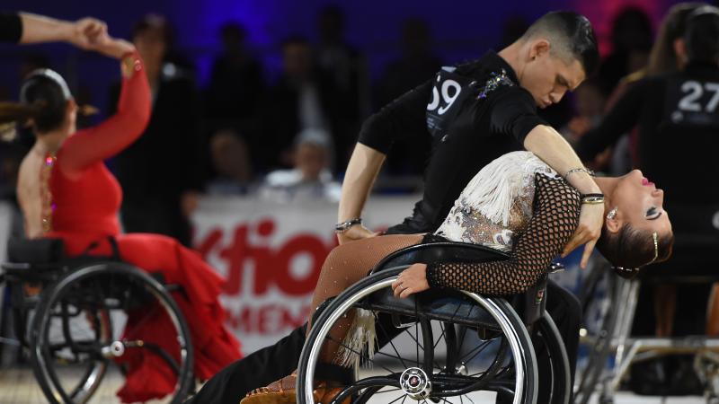 Standing male dancer dips his female wheelchair dancer