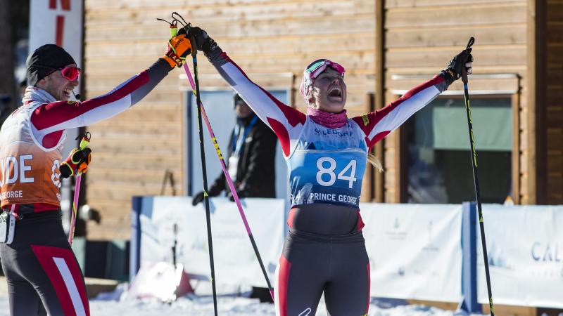 Cross-country skier lifts arms with joy with her guide on the side