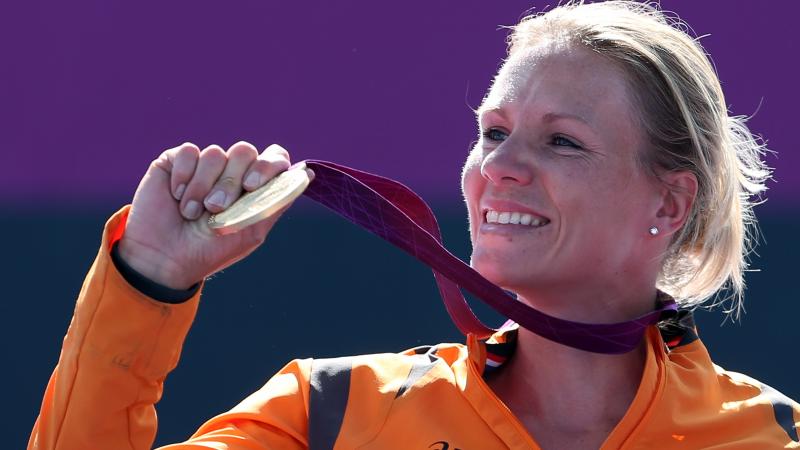 Dutch wheelchair tennis player smiles holding her gold medal at the London 2012 Paralympics