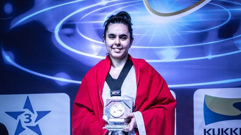 Female taekwondo fighter smiles holding prize