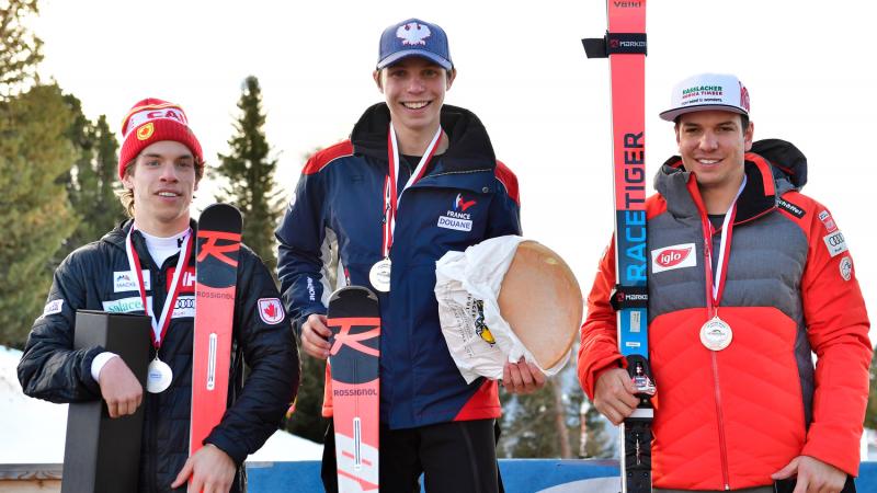 Male standing skiers on the podium