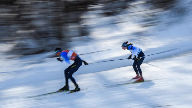 A male guide and a female athlete competing in Para biathlon