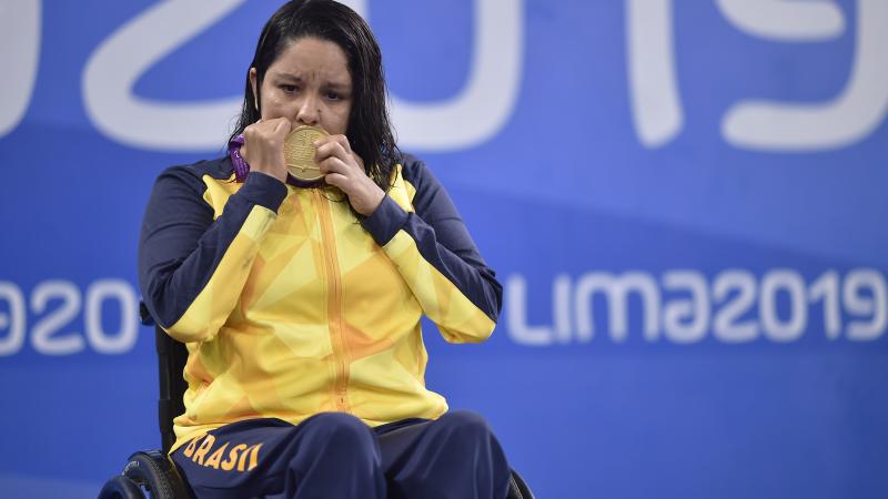 A woman in a wheelchair kissing a gold medal