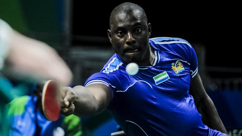 African table tennis player reaches for a shot