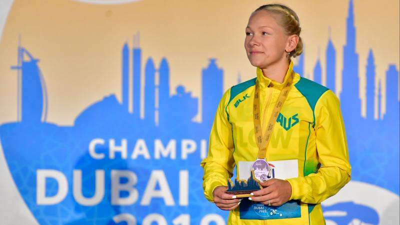 A woman with a medal standing on a stage