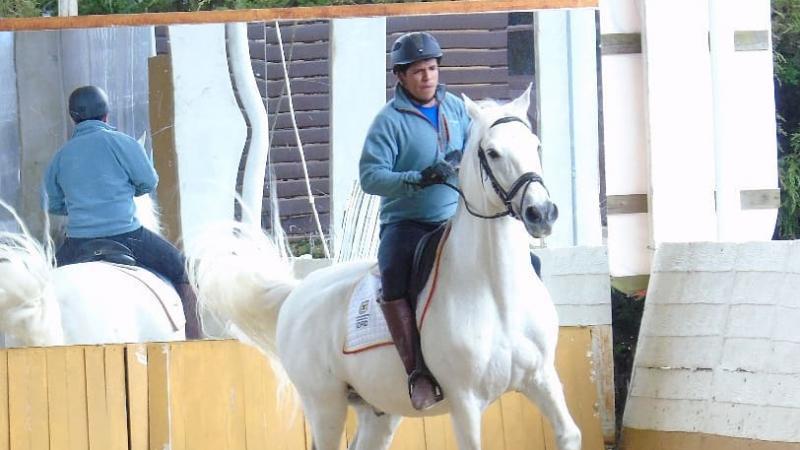 Man trains riding a white horse