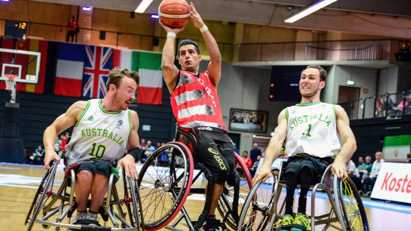 Two Australian men's wheelchair basketball players defend and Iranian athlete shooting the ball