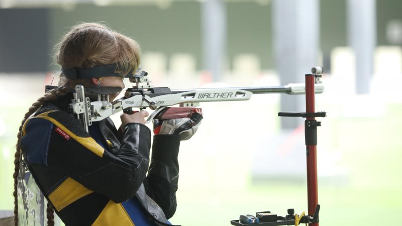 A woman competing in a shooting range with a rifle