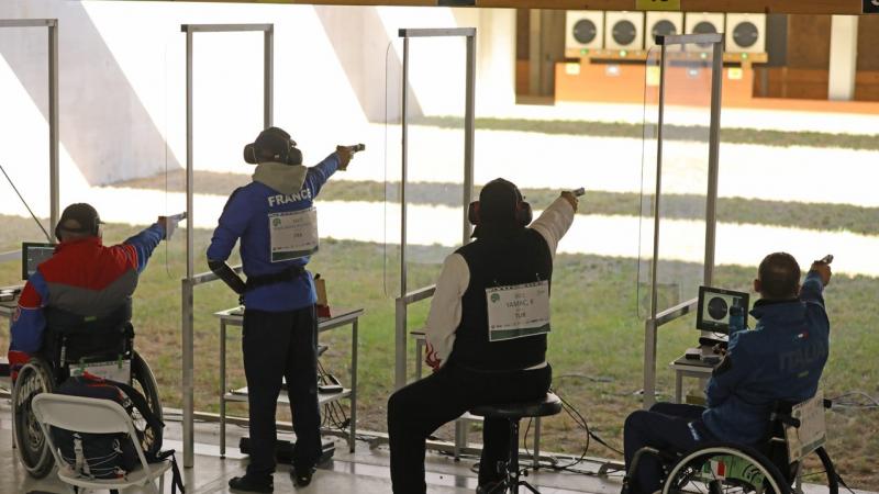 A group of four people competing with pistols in a shooting range