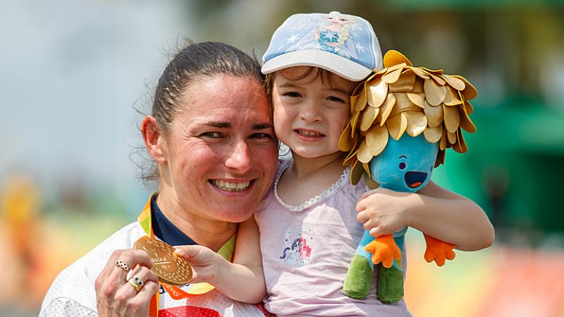 Sarah Storey cuddles her daughter and displays her gold medal